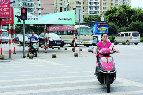 一女子骑电单车闯红灯过马路.