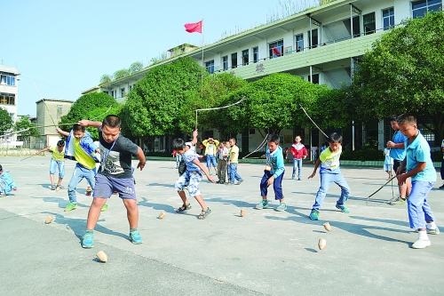 课间,孩子们在操场上打陀螺