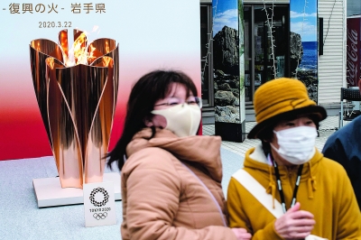 3月22日,在日本岩手县宫古,前来参观东京奥运圣火的人们戴着口罩.